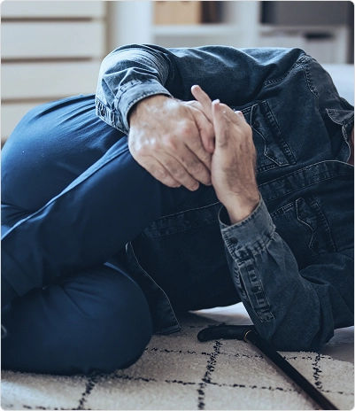 A man lying on the floor, holding his knee after falling.