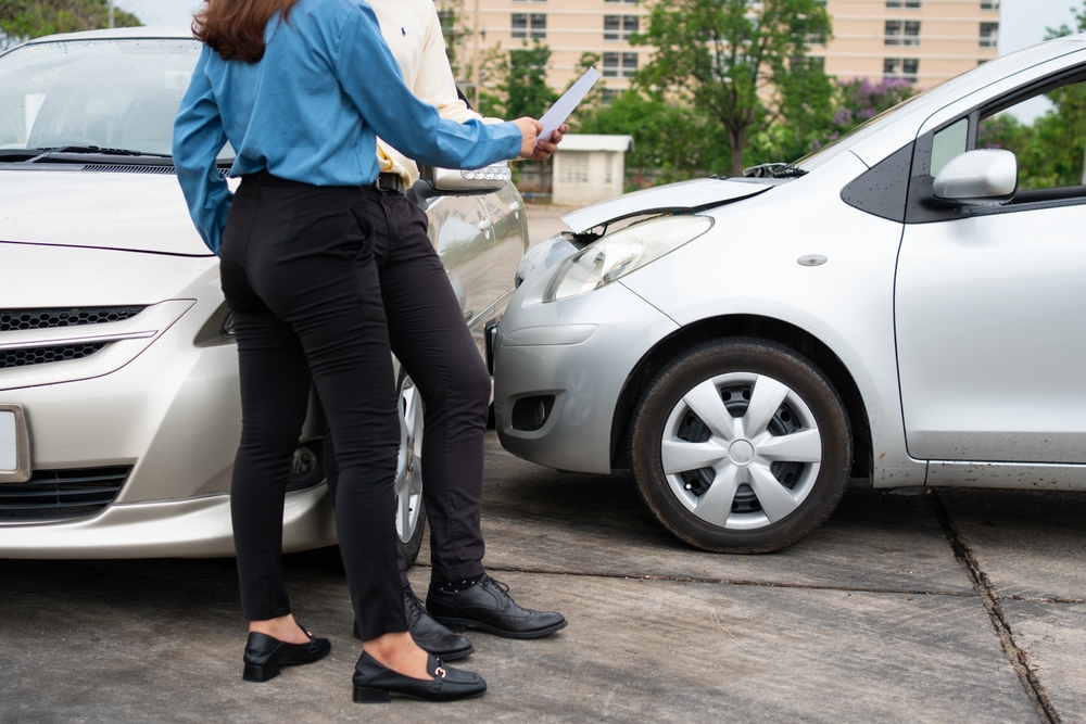 Two Drivers using a smartphone to exchange phone numbers and social media after a car accident