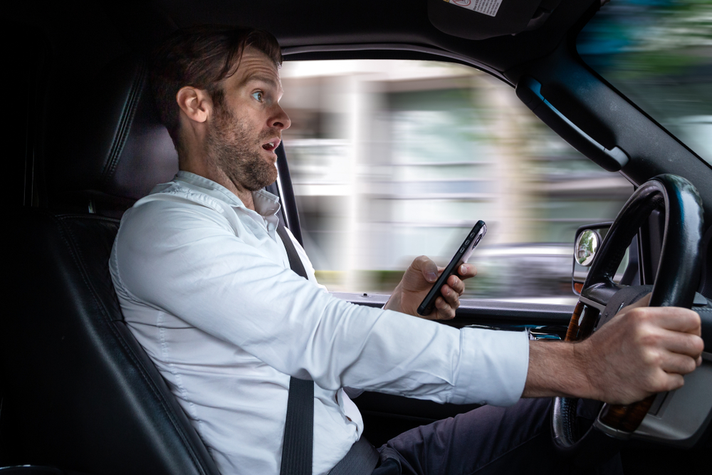 A middle aged caucasian man distracted driving while using a mobile device stops his vehicle suddenly to avoid an accident