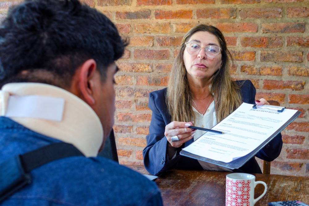 Mature adult female lawyer assist a injured man with legal problem. Lawyer showing document.