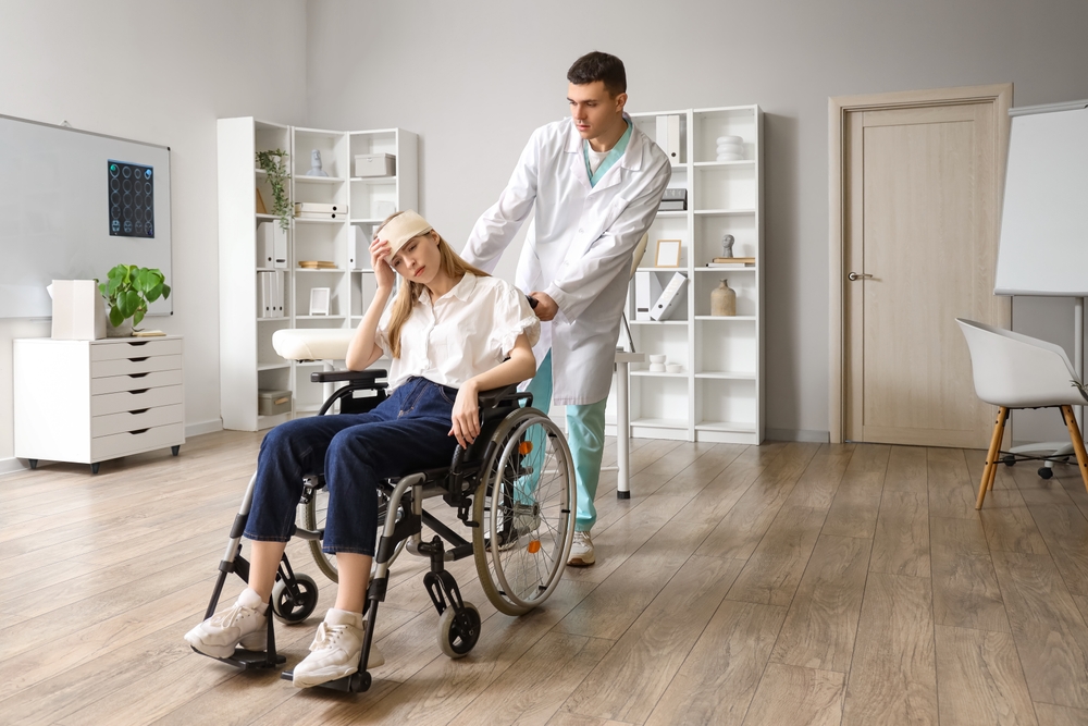 Young woman with brain concussion in wheelchair and doctor at hospital